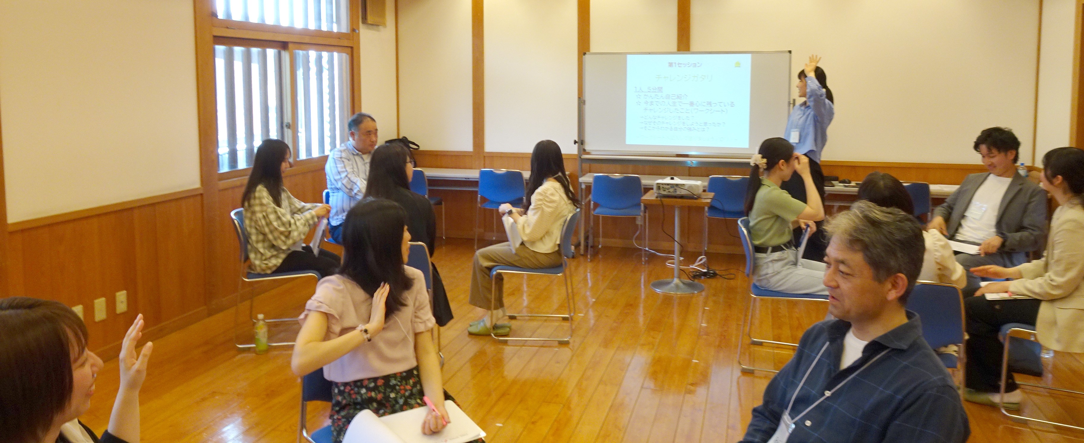 グループになって集まり、進行係に合わせて手を挙げている写真